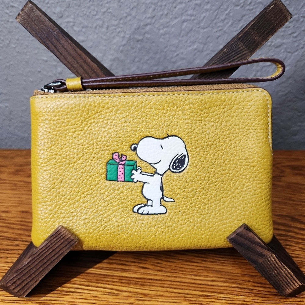 Coach X Peanuts Corner Zip Wristlet featuring a Snoopy present motif